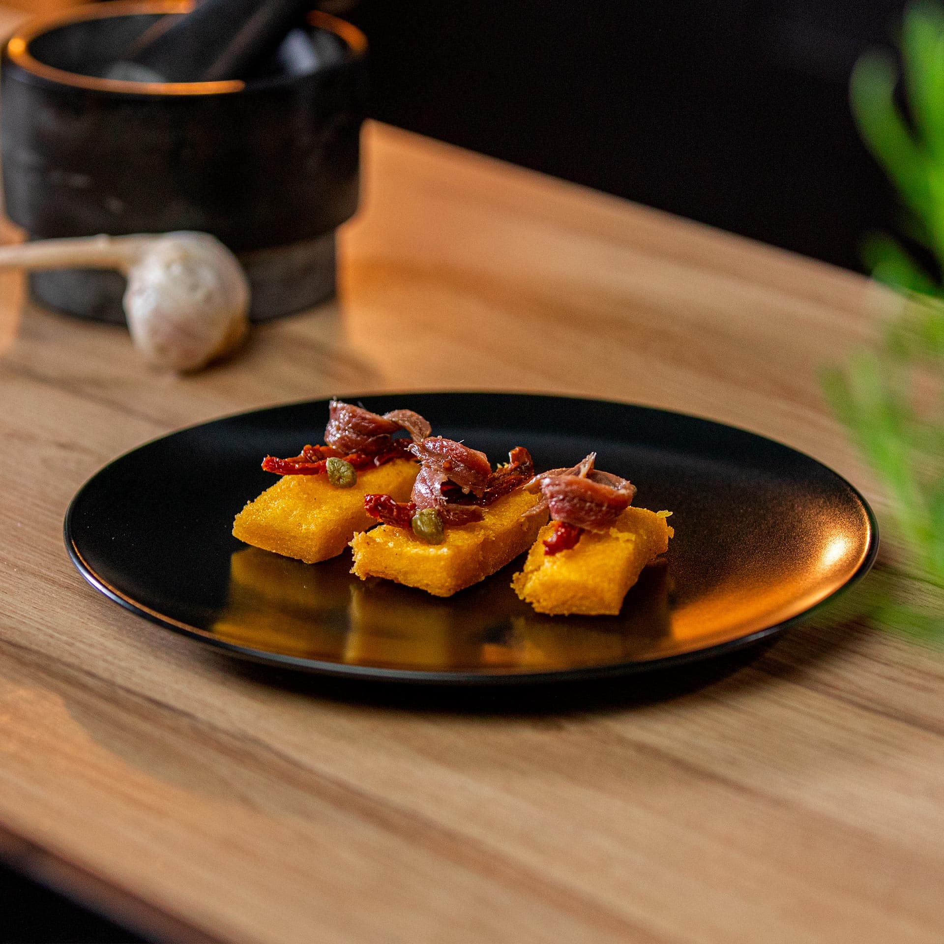 Chips di polenta con pomodorini secchi, capperi e acciughe